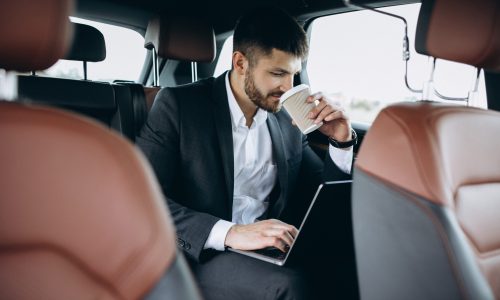 Handsome business man working on a computer in car